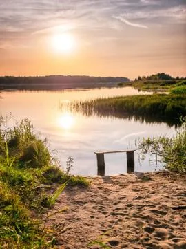 Empty bench near the river at sunset. Away from the hustle and bustle. Sun Stock Photos