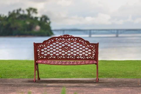 Empty bench, ocean, green grass, cloudy sky Stock Photos