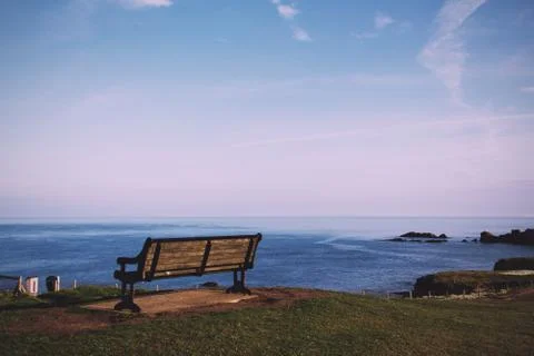 Empty bench over looking the coast in Bude, Cornwall Vintage Retro Filter. Stock Photos