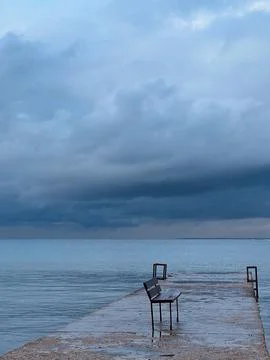 Empty bench on the pier with no people. Storm weather, sea Stock Photos
