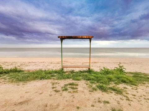 Empty bench by the sea on a cloudy day. Stock Photos