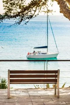 Empty bench with sea view of sailing boat at bay Stock Photos