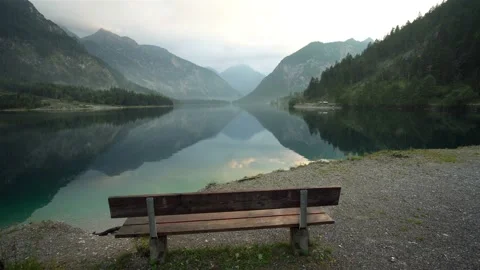 Empty bench stands near with a calm lake in Austria at sunset Video stock 121356302