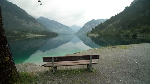 Empty bench stands near with a tranquil lake in Austria Vídeos de archivo 121356555