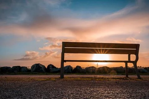 Empty bench at sunrise with sun rays across it. tranquility concept. landsc.. Stock Photos