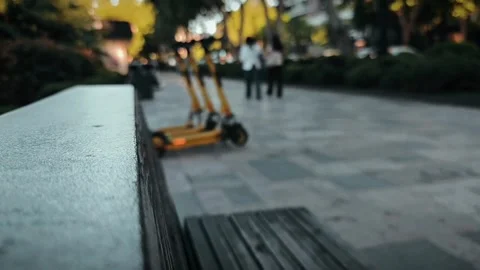 Empty bench in urban park with electric scooters Vidéo 310408525