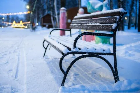 Empty bench in winter in the evening park. Snow bench without people Foto stock