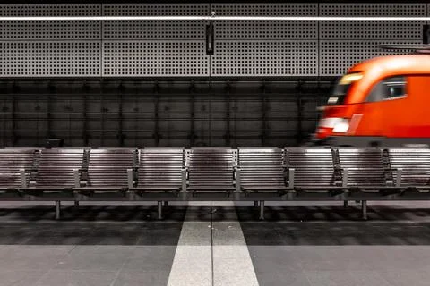 Empty benches on platform and blurred red train. Concept of speed and waiti.. Stock Photos