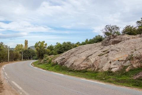 Empty bending road along a rocky knoll Stock Photos