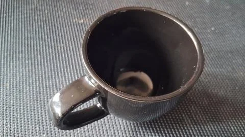 Empty black ceramic mug sitting on a dark textured surface Stock Photos