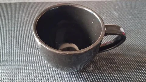 Empty black ceramic mug sitting on a textured grey surface 库存照片