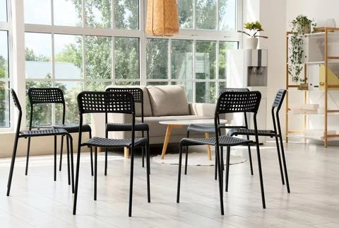 Empty black chairs arranged in a circle for a group therapy session or meetin Stock Photos