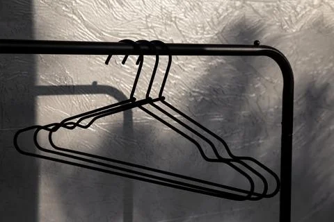 Empty black clothes hanger on gray wall background, close up. Stock Photos