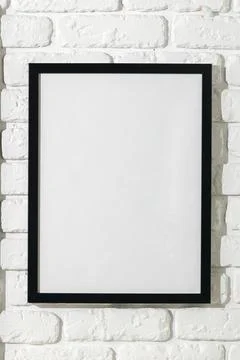 Empty black frame on a white brick wall in a simple indoor setting during Stock Photos