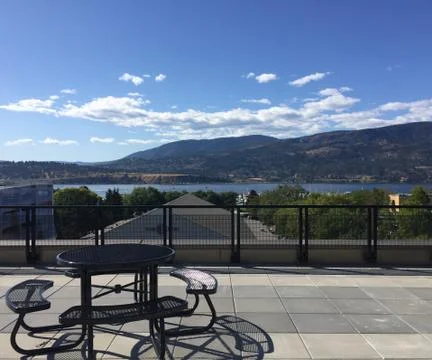 Empty black metal table and seating on rooftop overlooking lake and mountains Stock Photos