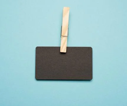 Empty black paper rectangular business card with wooden clothespins on a blue Stockfoto's