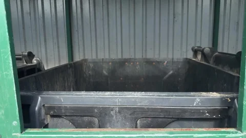 Empty black plastic waste container inside a fenced garbage area 動画素材 341510463