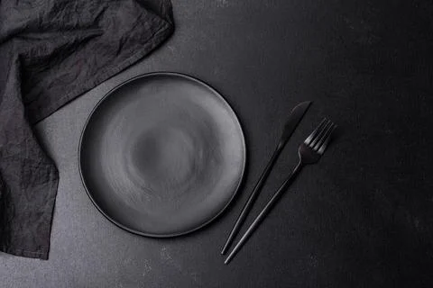 Empty black plate over dark stone background with free space. Top view Stock Photos