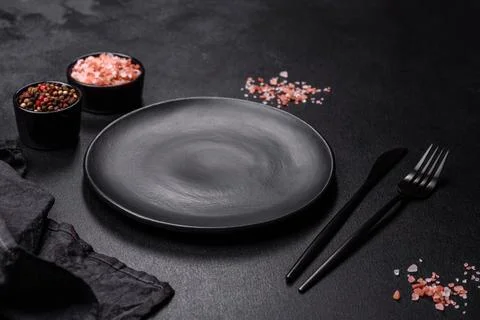Empty black plate over dark stone background with free space. Top view Stock Photos