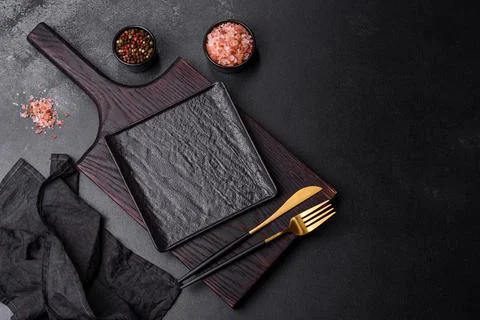 Empty black plate over dark stone background with free space. Top view Stock Photos