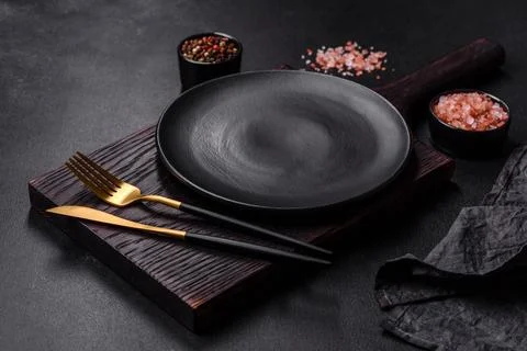 Empty black plate over dark stone background with free space. Top view Stock Photos