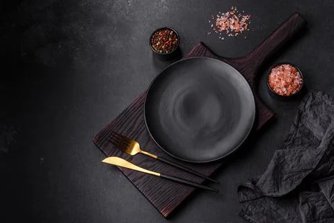 Empty black plate over dark stone background with free space. Top view Stock Photos