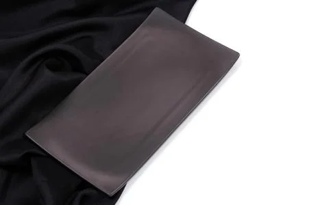 Empty black rectangle modern ceramic plate with silk tablecloth texture on wh Stock Photos