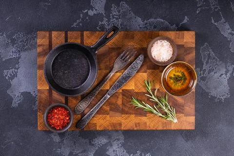 Empty black round  iron pan with handle on  wooden cutting board. Stock-Fotos