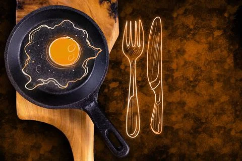 Empty black round iron pan with painted egg on wooden cutting board. Stock Photos