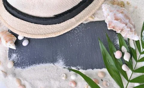 Empty black slate on the sand with hat and shells Stock Photos