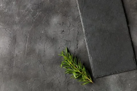 Empty black stone board and rosemary on dark background. Copy space for tex.. Stock Photos