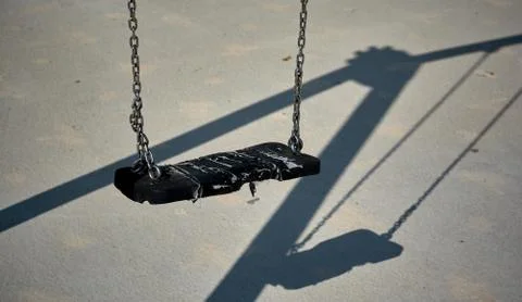 Empty black swing and its shadow Stock Photos