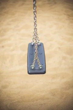 Empty black swing hanging over the sand Stock Photos