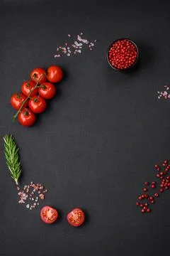 Empty black texture table, cherry tomatoes on a twig, spices, salt and herbs Stock Photos