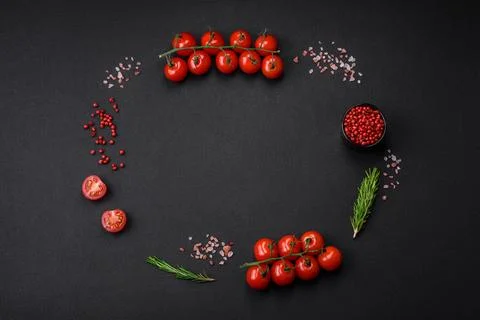 Empty black texture table, cherry tomatoes on a twig, spices, salt and herbs Stock Photos