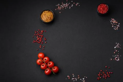 Empty black texture table, cherry tomatoes on a twig, spices, salt and herbs Stock Photos