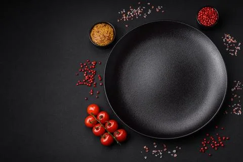 Empty black texture table, cherry tomatoes on a twig, spices, salt and herbs Stock Photos