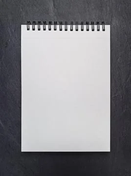 Empty blank page of notepad on black slate background. Mockup. Flat lay Stock Photos