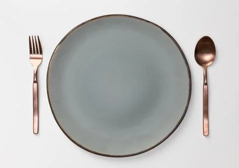 Empty blank white ceramic round plate or dish with spoon and fork isolated .. Stock Photos