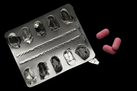 Empty blister pack and three pink pills isolated Stock Photos