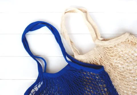 Empty blue and beige net bags on wooden background Stock Photos