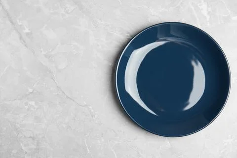 Empty blue ceramic plate on light grey marble table, top view. Space for text Stock Photos