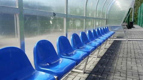 Empty blue plastic seats in outdoor sport stadium players bench Stock Footage 126909027