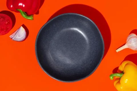 Empty blue plate on orange background with tomato, pepper, onion and garlic. Stock Photos