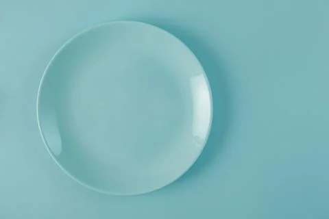 Empty blue plate on same colored blue background. Top view Stock Photos