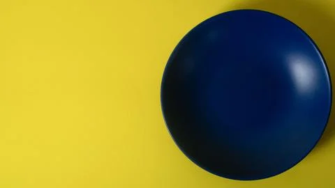 Empty blue plate on yellow background. Flat lay with copy space Stock Photos