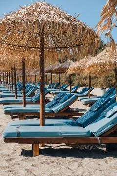 Empty blue sun beds under the umbrellas on a beach in Mykonos, Greece. Stock Photos
