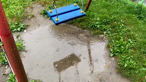 Empty blue wooden swing swinging in the rain Stock Footage 166314145