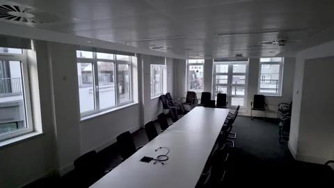 An empty boardroom features a long table surrounded by chairs bathed in natural Stock Footage 325838754