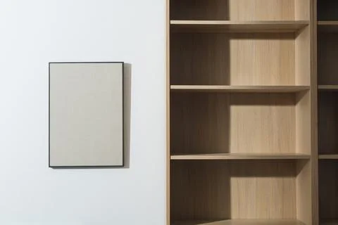 Empty bookcase and blank picture hanging on the wall Stock Photos
